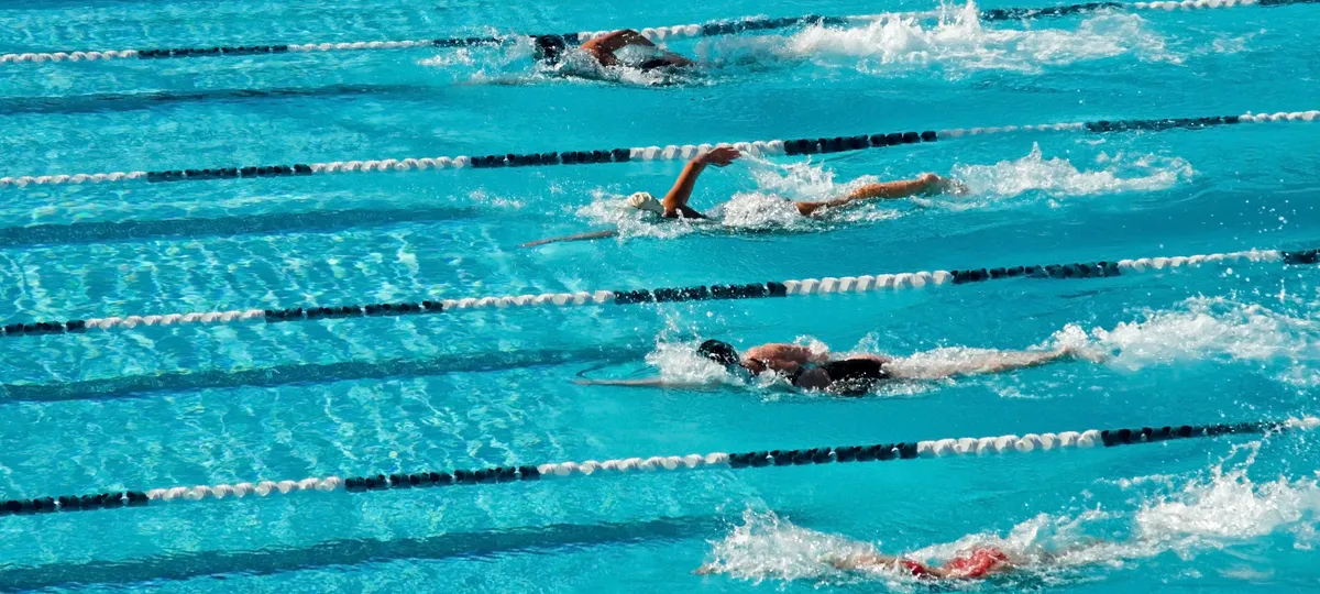 Competitive swimmers racing in pool lanes during high school swim meet