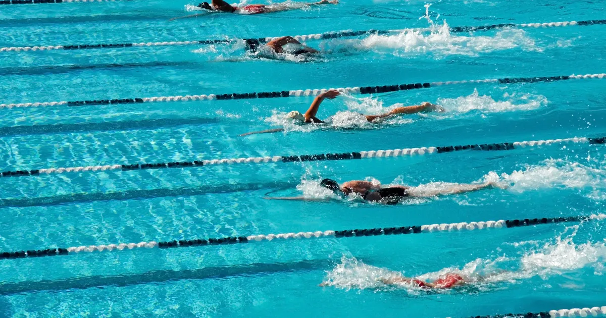 Competitive swimmers racing in pool lanes during high school swim meet